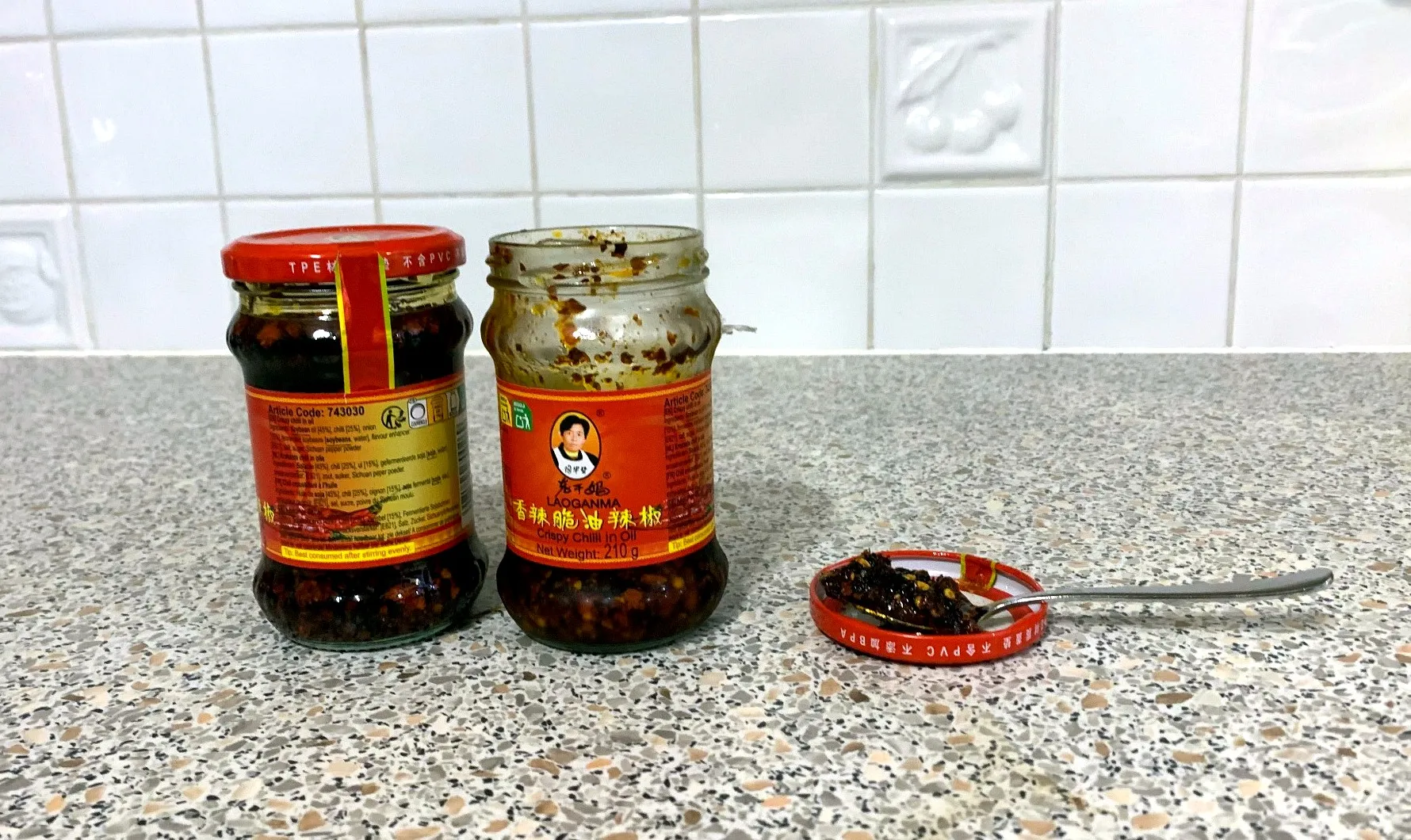 Two jars of Lao Gan Ma crispy chilli oil with a spoonful ready to serve
